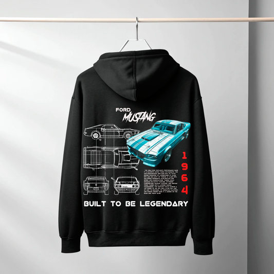 A black hoodie hanging on a hanger against a light gray wall, featuring a large back graphic of a 1964 Ford Mustang with blueprint-style drawings, a turquoise car illustration, and the text 'FORD MUSTANG', 'BUILT TO BE LEGENDARY', and '1964'.